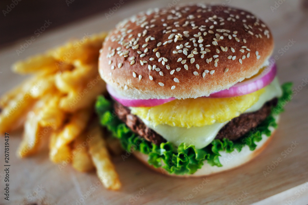 A served hamburger with a pineapple topping in the middle. A served hamburger with a pineapple topping in the middle.
