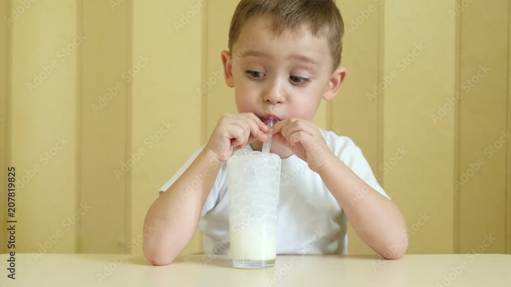 The child lets the bubbles into the milkshake through the straw in a slow motion The child lets the bubbles into the milkshake through the straw in a slow motion