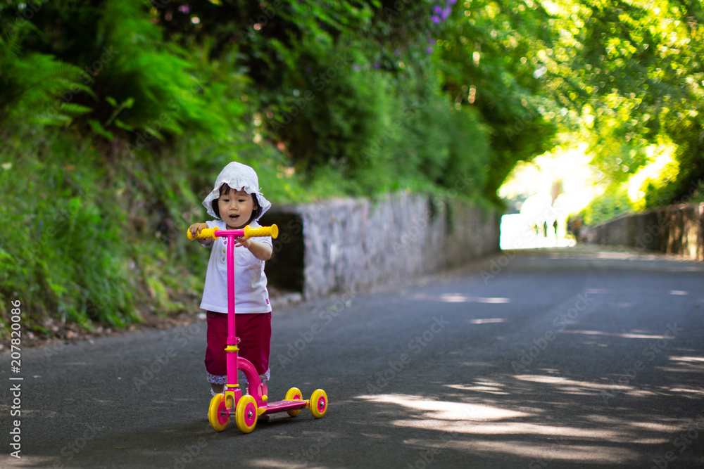 baby girl play balance scooter at summer park baby girl play balance scooter at summer park