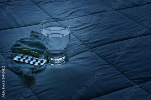 Blister pack of sleeping pills, blindfold and glass of water photo