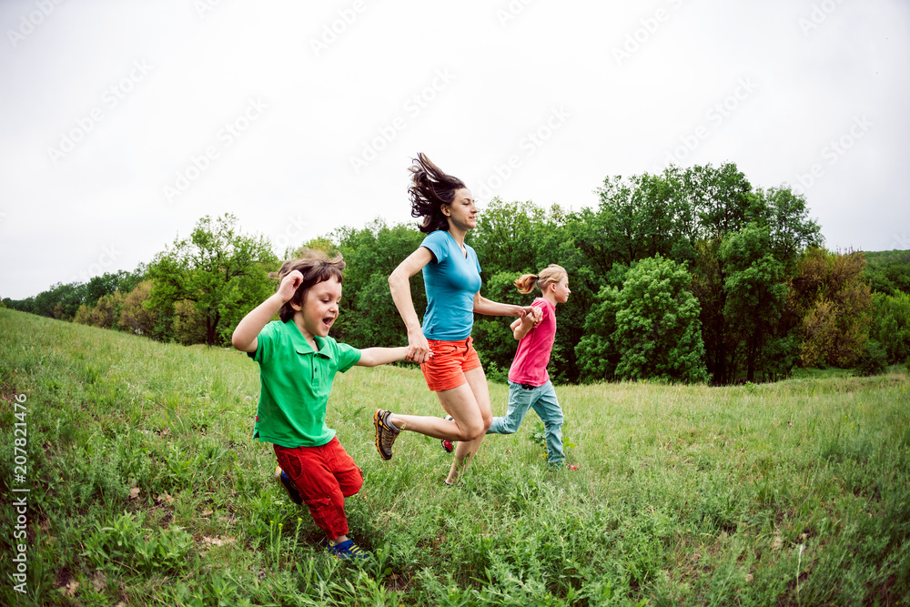 A woman with children runs along the grass.