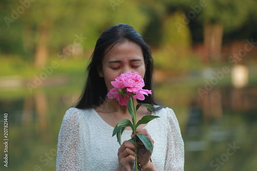 Красивая азиатская девушка в белом платье с розовым цветком пиона