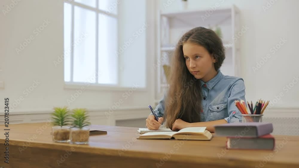 Young girl with laptop computer is doing homework. College education. Female student is studying at home. Young girl with laptop computer is doing homework. College education. Female student is studying at home.