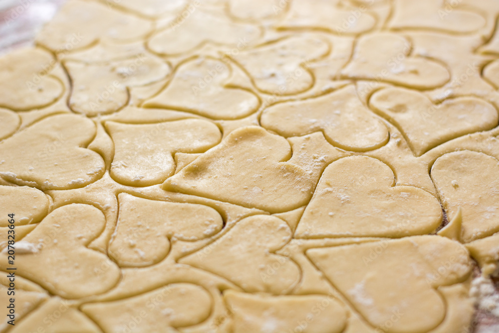 Preparation of the dough, roll out with a rolling pin and cut shapes in the form of hearts. Baking cookies for the holiday. Close-up.