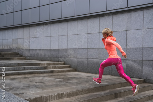 Athletic young woman running on background of urban landscape. Healthy lifestyle.