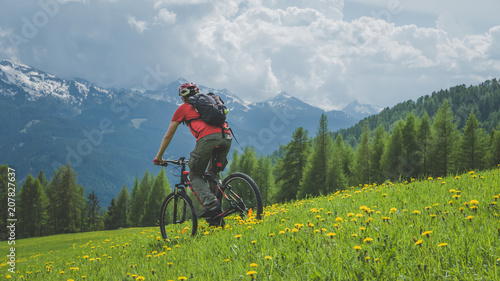MTB bicycle ride in the mountain meadow, rear view of cyclist in