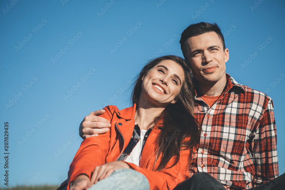 Love is silent. Beautiful couple sitting close to each other watching sunset with smiles. They are joyful and calm Love is silent. Beautiful couple sitting close to each other watching sunset with smiles. They are joyful and calm