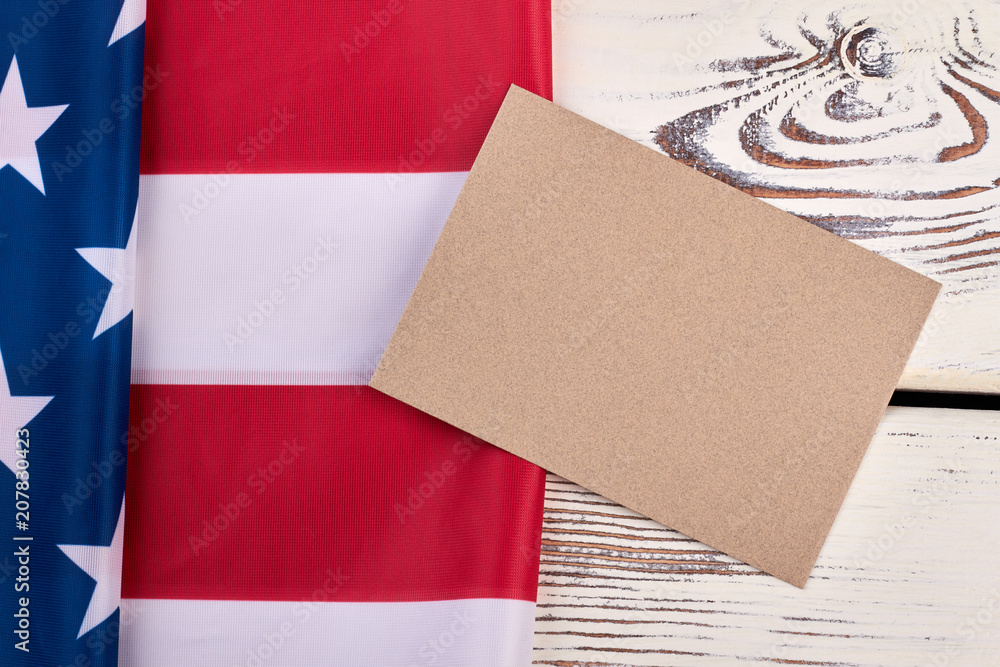 Fototapeta premium American flag on white wooden background. Flag of America and envelope from craft paper on vintage wood.