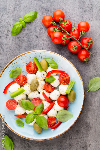 Delicious caprese salad with ripe cherry tomatoes and mini mozzarella cheese balls with fresh basil leaves.