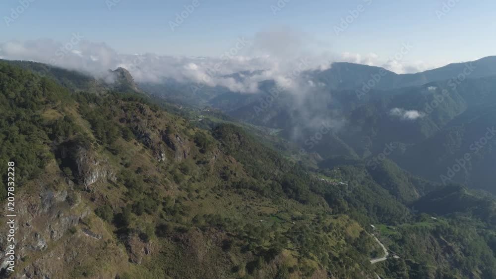 Aerial view of mountains covered forest, trees in clouds. Cordillera region. Luzon, Philippines. Slopes of mountains with evergreen vegetation. Mountainous tropical landscape. Aerial view of mountains covered forest, trees in clouds. Cordillera region. Luzon, Philippines. Slopes of mountains with evergreen vegetation. Mountainous tropical landscape.