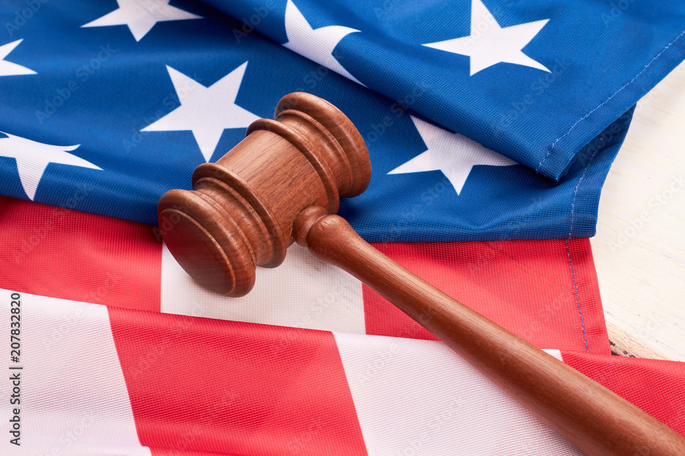 Close up wooden gavel and American flag. Judge gavel and flag of United States of America. Law and justice.