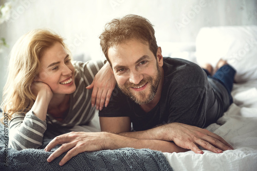 фотографія Cheerful bearded man is lying with soulmate on bed