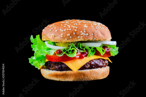 Big tasty hamburger or cheeseburger isolated on black background with grilled meat, cheese, tomato, bacon, onion. Burger closeup