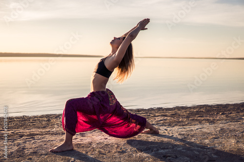 Silhouette yoga woman on the beach at sunset. Morning natural training photo