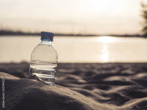 close up bottle with water on the sea coast in sand