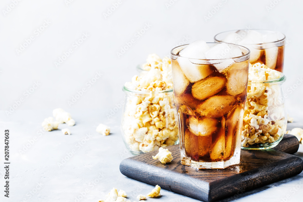 Cola with ice and sweet popcorn, ready for cinema, gray background, selective focus Cola with ice and sweet popcorn, ready for cinema, gray background, selective focus