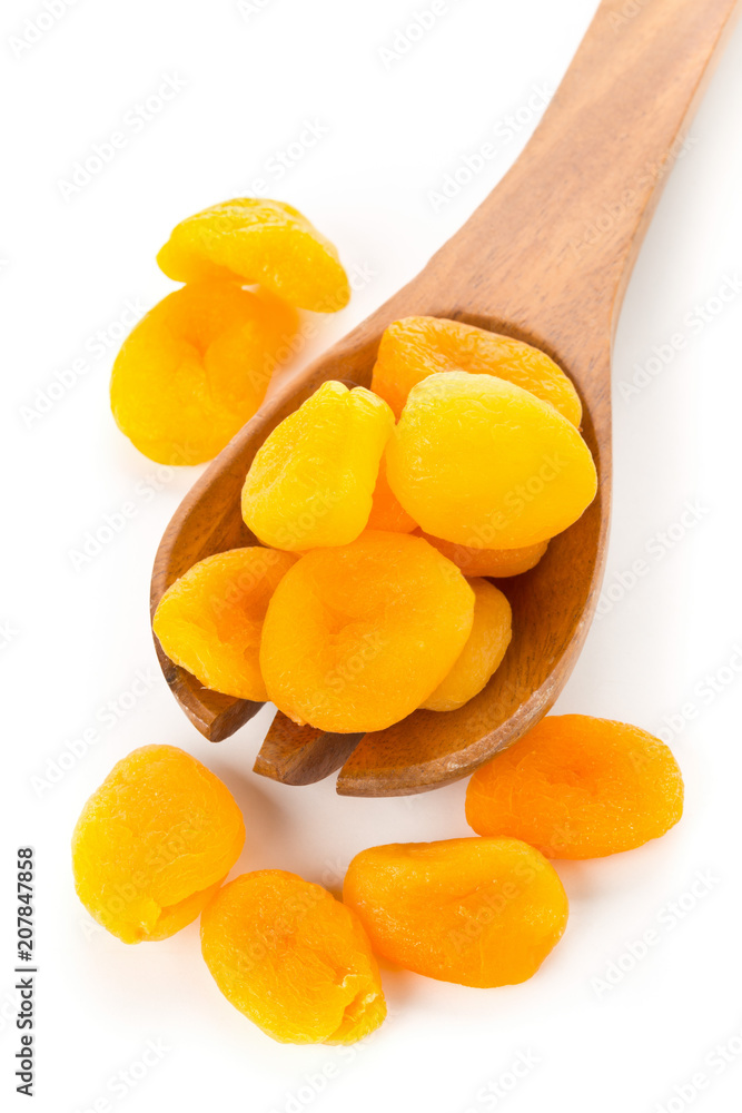 Whole dried apricots fruit in wooden spoon over white Whole dried apricots fruit in wooden spoon over white