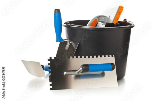 Masonry tools - trowels, notched trowel and mortar bucket - on white photo