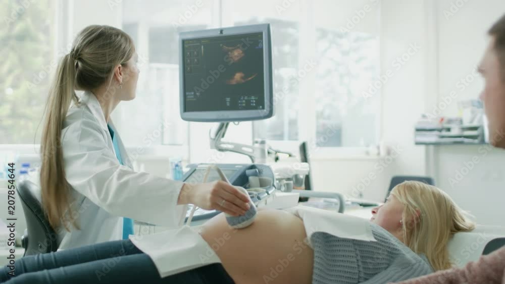 In the Hospital, Pregnant Woman Getting Ultrasound / Sonogram Scan, Obstetrician Explains Procedure to Her and Her Supportive Husband. Shot on RED EPIC-W 8K Helium Cinema Camera. In the Hospital, Pregnant Woman Getting Ultrasound / Sonogram Scan, Obstetrician Explains Procedure to Her and Her Supportive Husband. Shot on RED EPIC-W 8K Helium Cinema Camera.