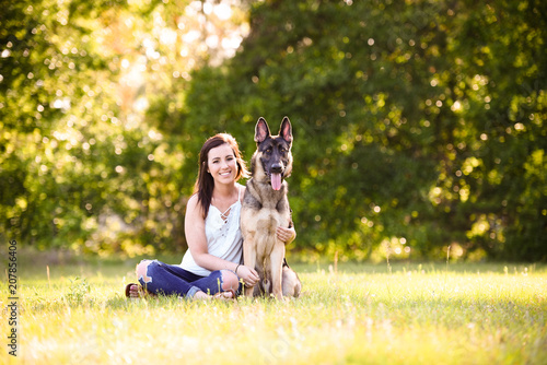Young woman with German Shepherd dog in the gorgeous summer field