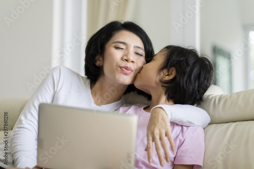 Little girl playing a laptop with her mother