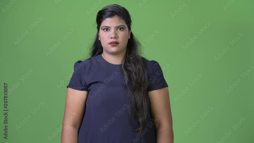 Young overweight beautiful Indian businesswoman against green background Young overweight beautiful Indian businesswoman against green background