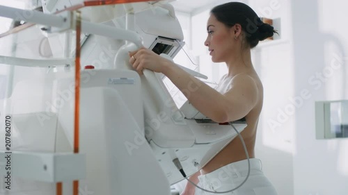 In the Hospital, Mammography Technologist / Doctor Pushes Button on Mammogram Machine Activating Female Patient Scan.  photo