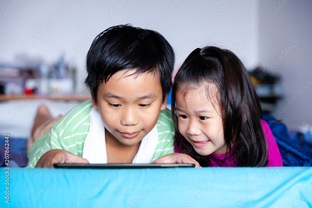 Asian children watching video and playing game on digital tablet. Asian children watching video and playing game on digital tablet.