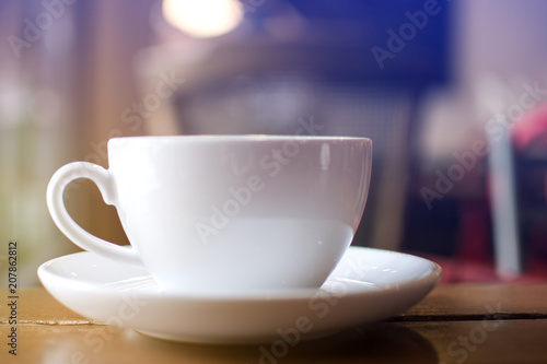 Close up white cup with soft steaming hot coffee on table with bokeh background at coffee shop