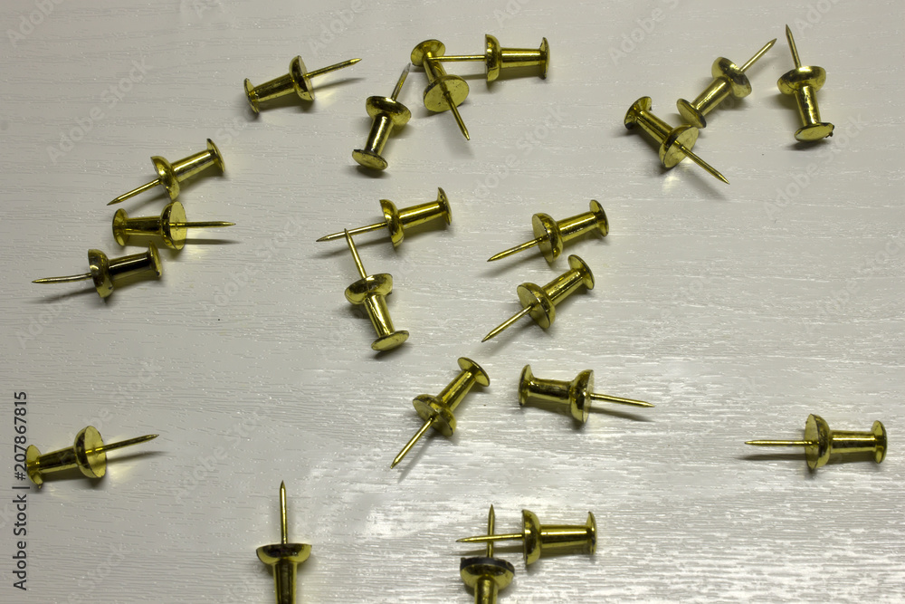 Gold Push pins isolated on a textured White background Gold Push pins isolated on a textured White background