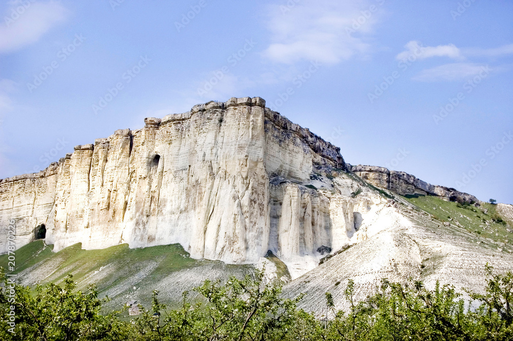 mountain white frome limestone in Crimea with caves blue sky and green near mountains mountain white frome limestone in Crimea with caves blue sky and green near mountains