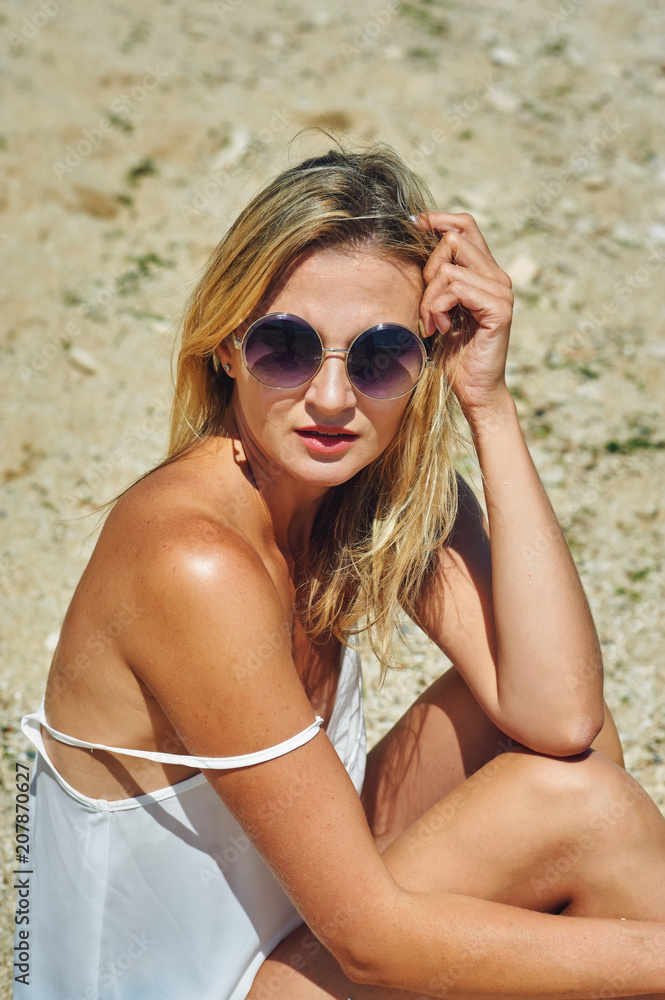 Portrait of a young woman wearing sunglasses on the beach Portrait of a young woman wearing sunglasses on the beach