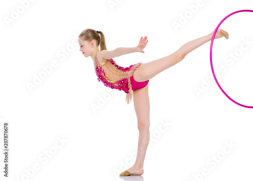 A girl gymnast performs an exercise with a hoop. © lotosfoto