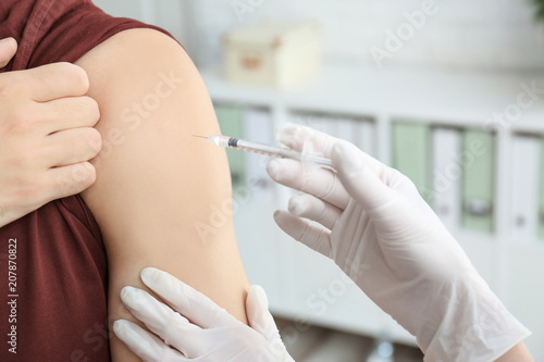 Doctor vaccinating male patient in clinic  closeup