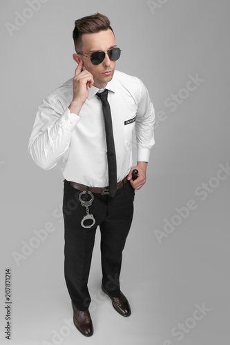 Male security guard in uniform on color background