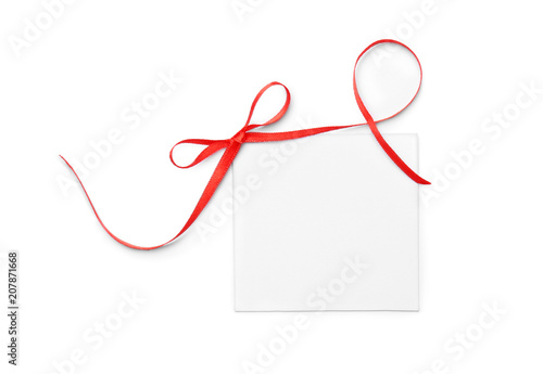 Blank gift tag with satin ribbon on white background, top view