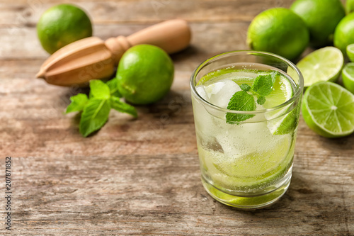 Refreshing beverage with mint and lime in glass on table