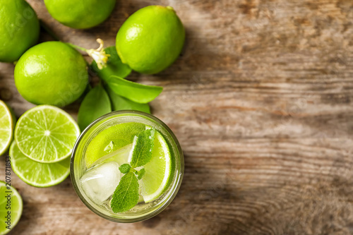 Refreshing lime beverage and ingredients on wooden background, top view