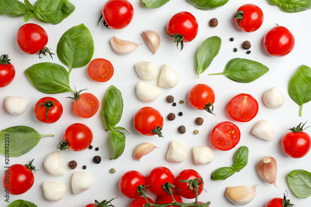Flat lay composition with tomatoes, mozzarella cheese balls, garlic and basil on light background Flat lay composition with tomatoes, mozzarella cheese balls, garlic and basil on light background
