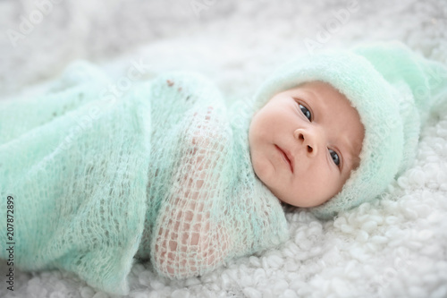Adorable newborn baby in warm hat lying on bed © New Africa