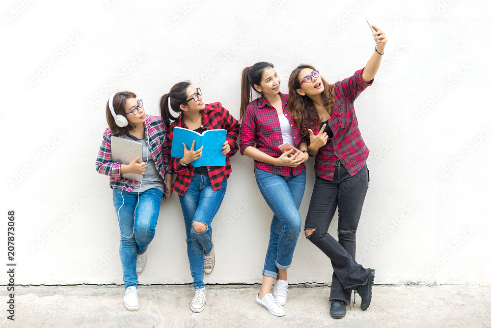 Obraz premium Asian group woman standing and holding a book, take a photo on wall white background. Education Concept