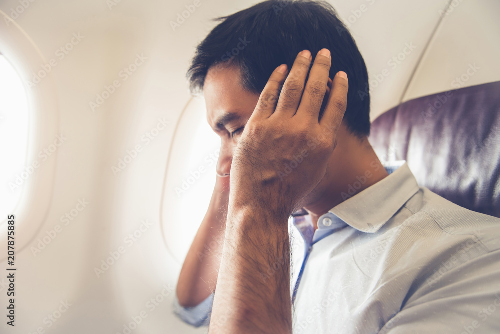 Naklejka premium Male passenger having ear pop on the airplane