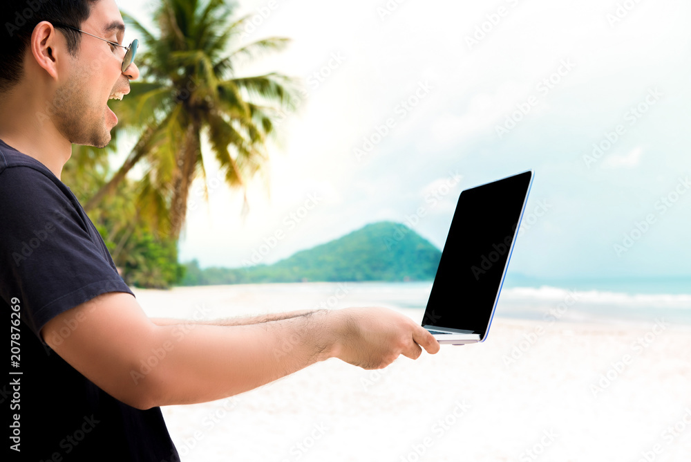 Happy casual man enjoying surfing internet at the beach