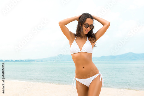 Young beautiful Asian woman in white biniki at the beach in summer