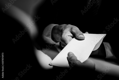 Businessman giving bribe money in the envelope to partner photo