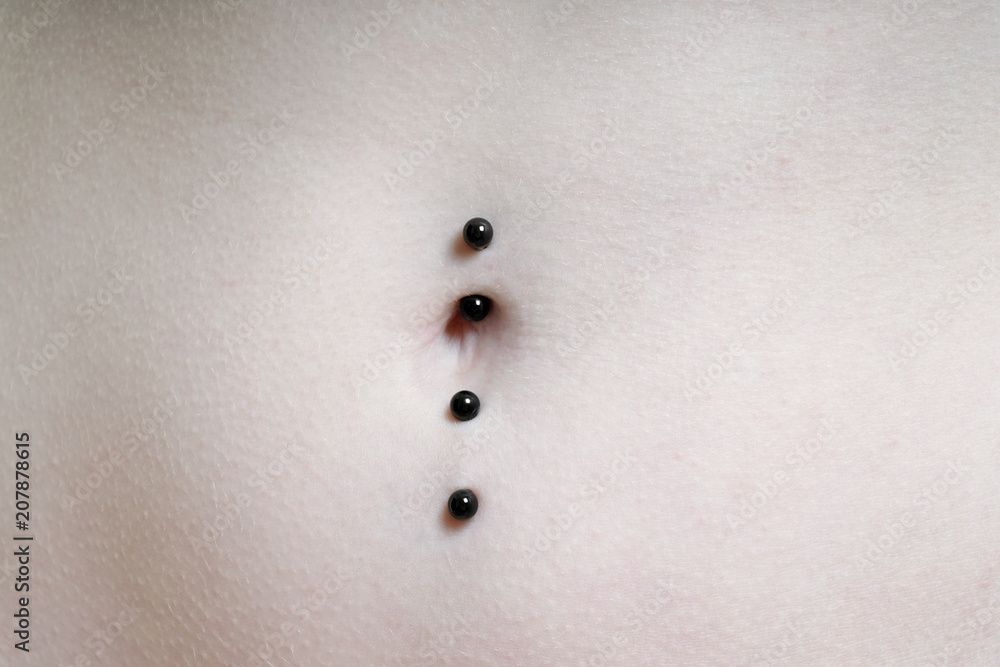 Obraz premium close-up of belly button or navel pierced with double barbell piercing
