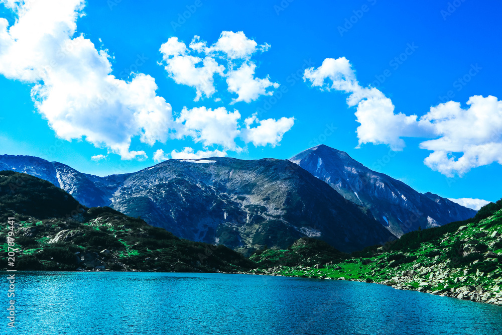 Beautiful alpine lake, river in the high mountains peak, blue sky background. Amazing Mountain hiking paradise landscape, summertime.