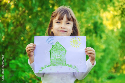 Drawing of a green house in the hands of a child. Selective focus.  photo