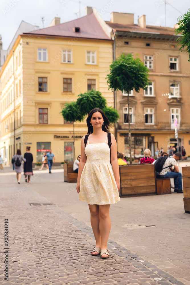 Young woman on an excursion in old city. Girl in yellow summer dress