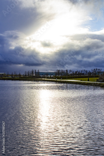 Sunlight Breaking through the Clouds over the Silver Tjörnin Pond at Hljómskálagarðurinn Park in Reykjavik, Iceland
